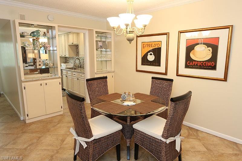 Dining room featuring crown molding, sink, a notable chandelier, and light tile floors