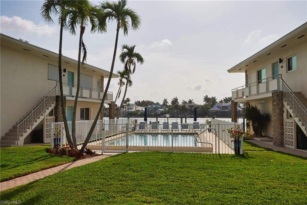View of property's community with a swimming pool and a lawn