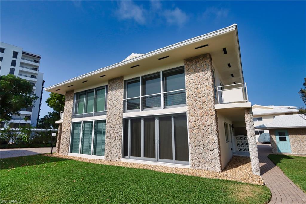 Rear view of house featuring a lawn and a balcony