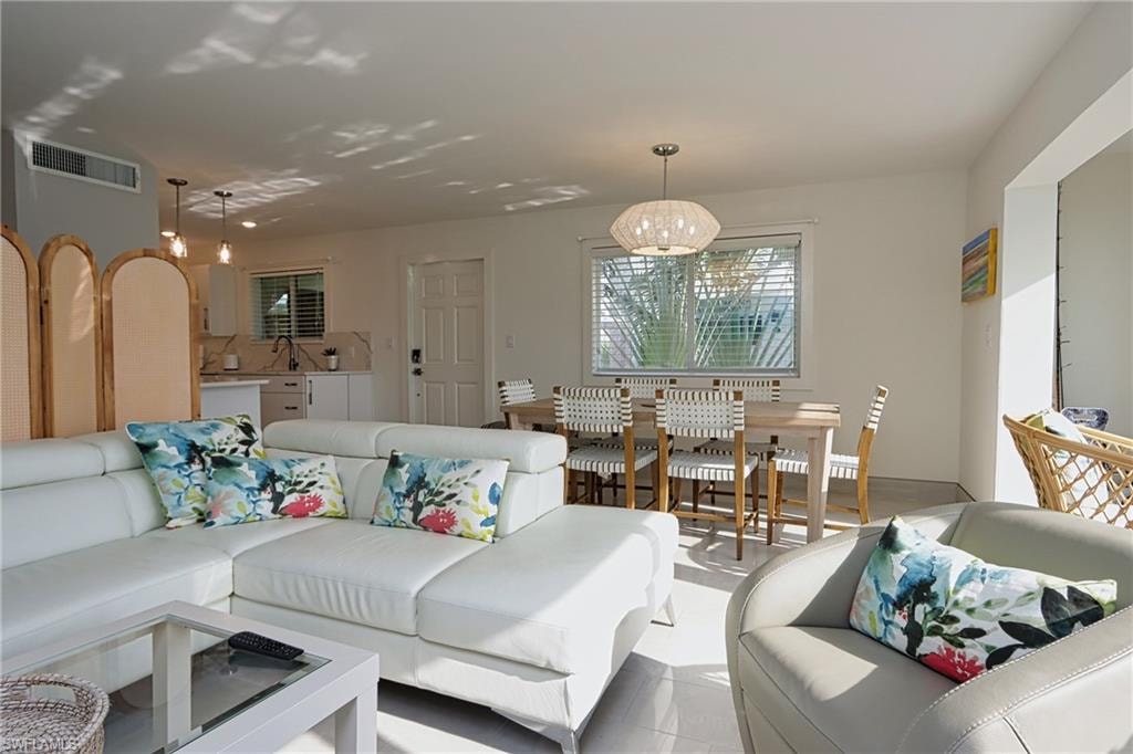 Living room with a notable chandelier, sink, and light tile flooring