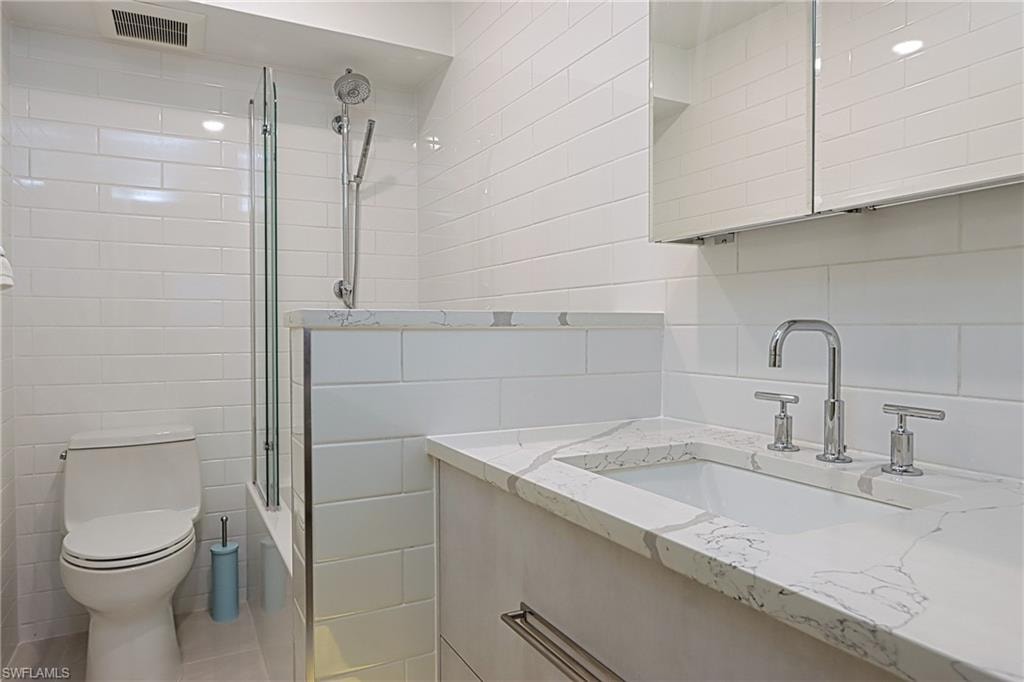 Bathroom with backsplash, tile walls, and toilet
