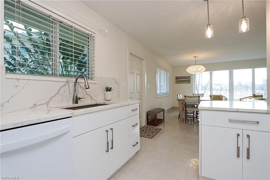 Kitchen with white cabinetry, tasteful backsplash, white dishwasher, and light tile floors