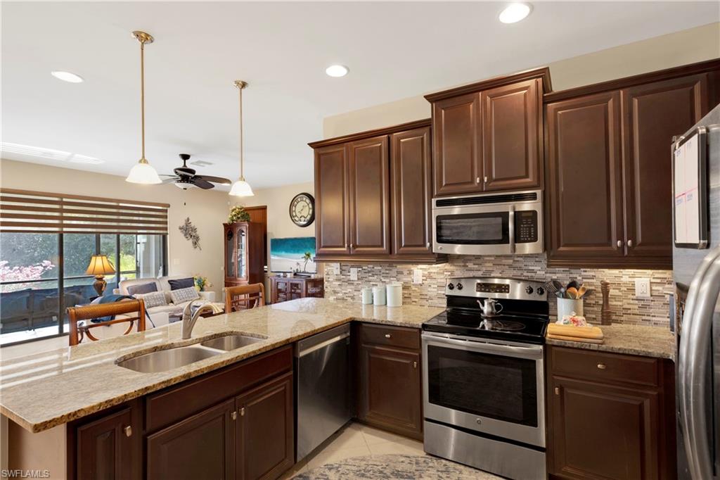 Kitchen with sink, hanging light fixtures, backsplash, stainless steel appliances, and kitchen peninsula