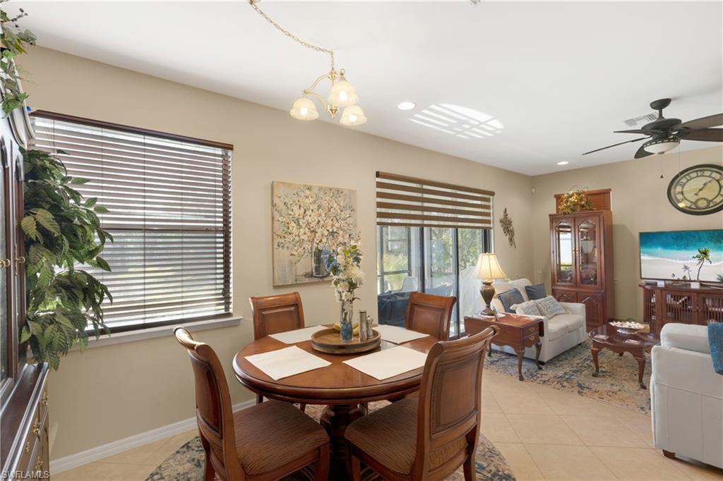 Tiled dining area with ceiling fan with notable chandelier