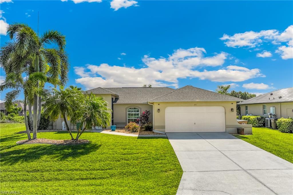 The property features a well-maintained front yard with a lush green lawn and mature palm trees.