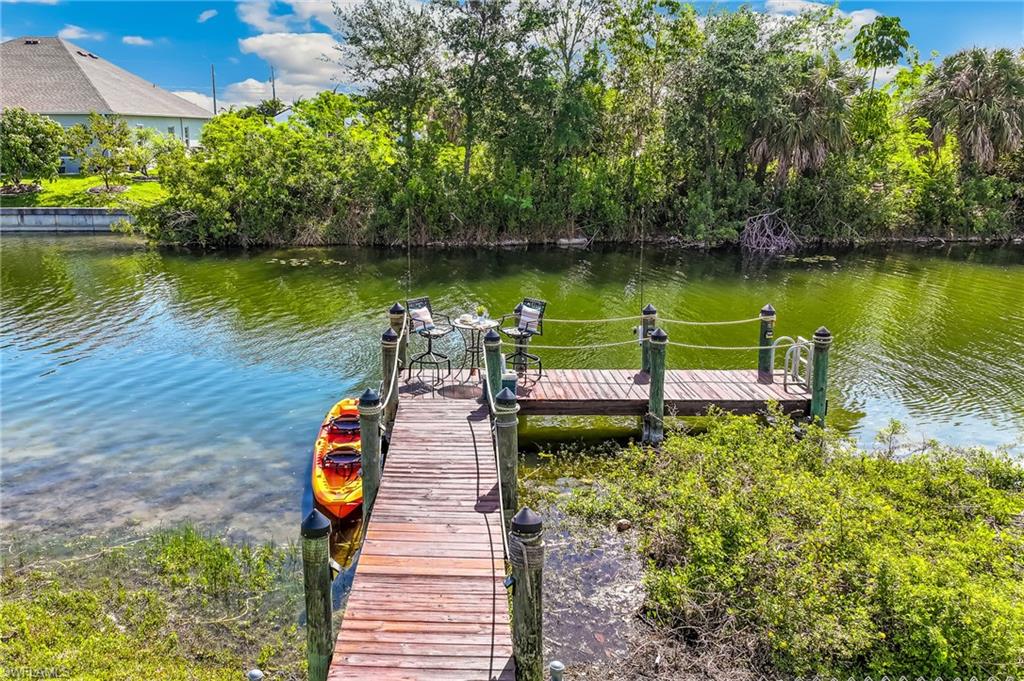 Private wooden dock extending into the waterway, featuring a seating area and lush natural surroundings.