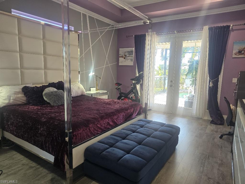 Room featuring wood-finish flooring, purple walls, and crown molding