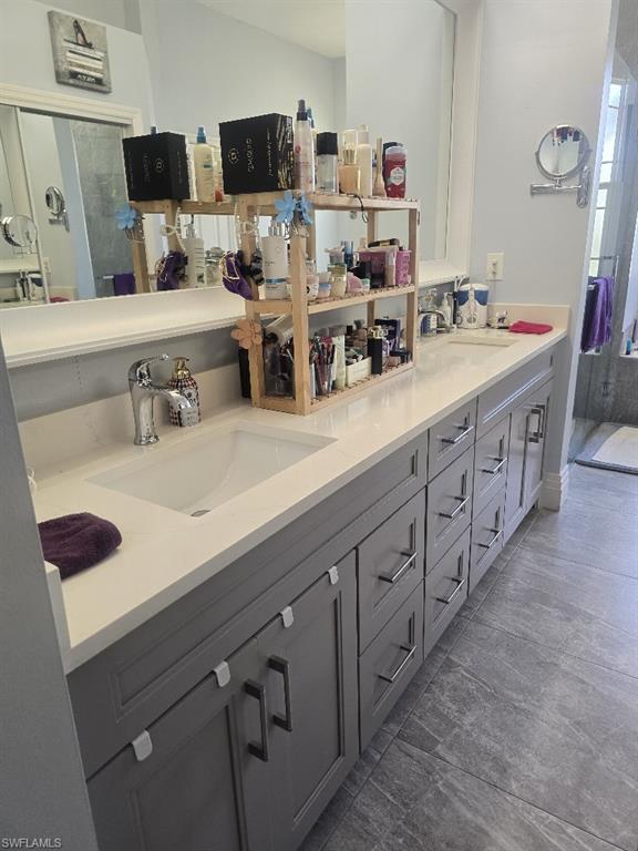 Dual under-mount sinks set into a light-toned countertop, complemented by a large back-lit mirror