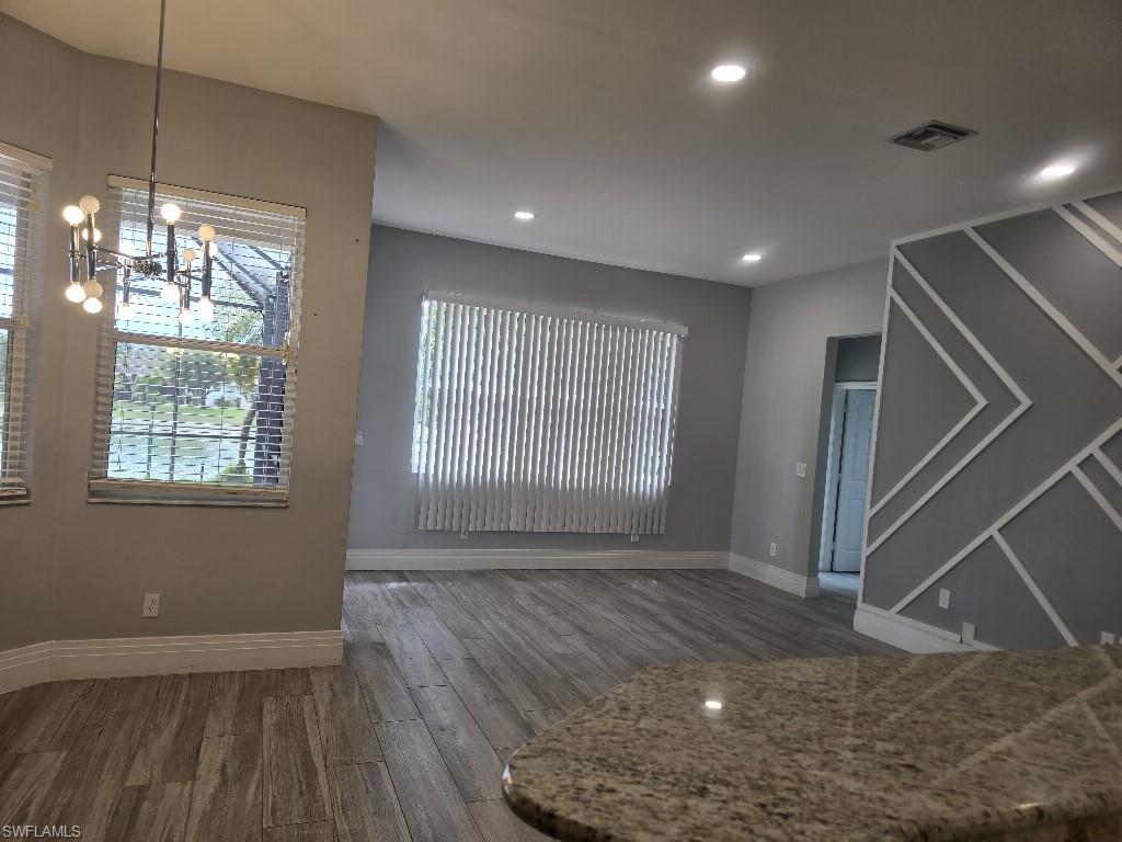 Open concept living area featuring wood-finish flooring, recessed lighting, and a decorative accent wall with geometric molding