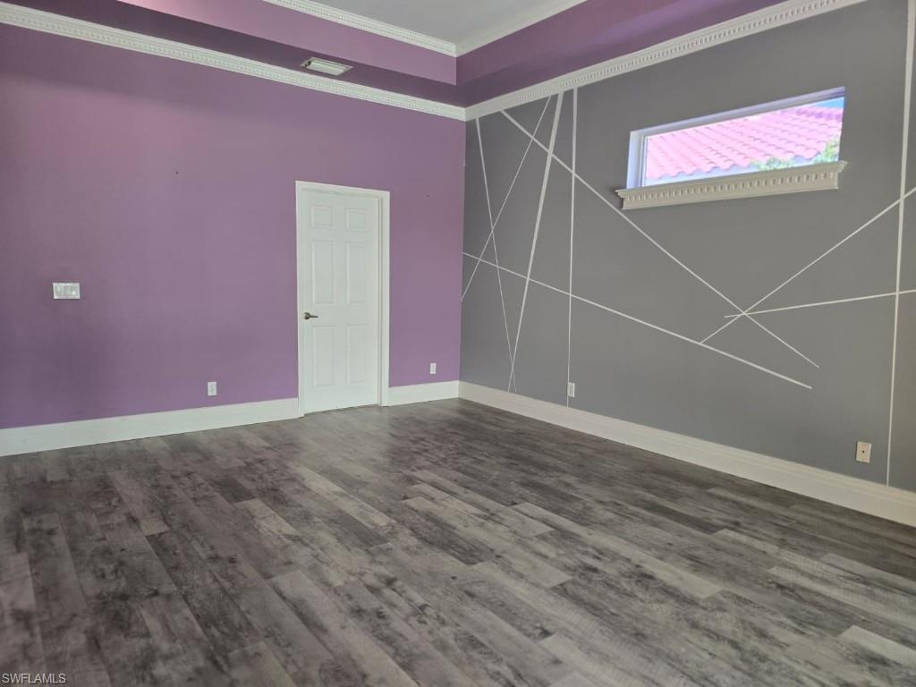 Room featuring wood-finish flooring, crown molding, and a vaulted ceiling