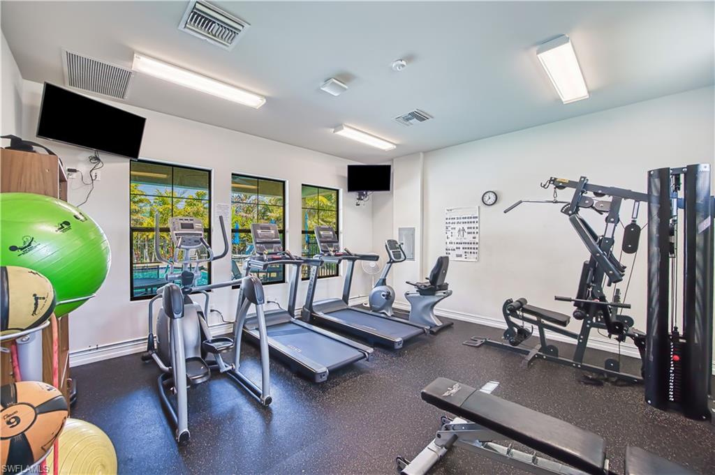 Fitness center with rubber flooring, multiple cardio machines, weight training equipment, and wall-mounted televisions