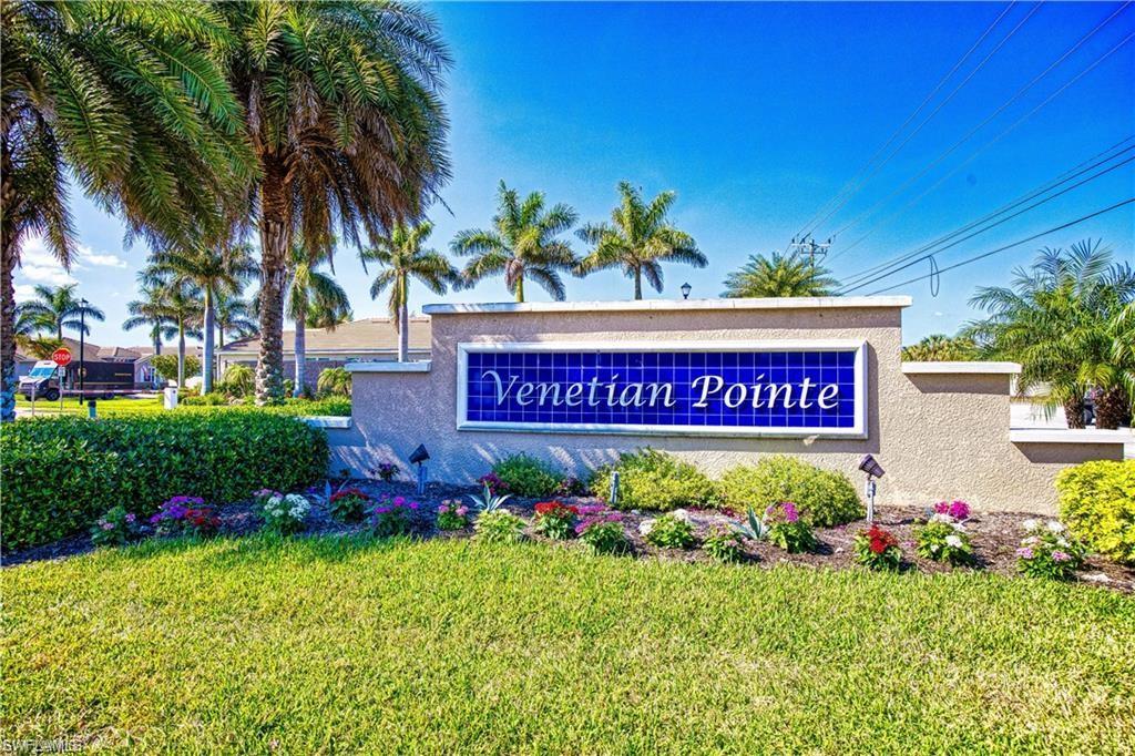 Venetian Pointe community entrance sign featuring blue tiled lettering, manicured landscaping, and mature palm trees