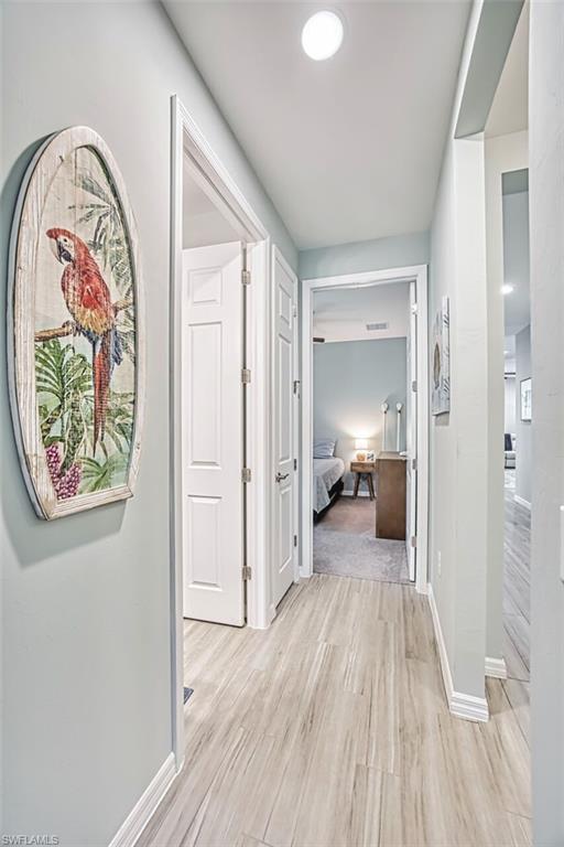Hallway featuring wood-finish flooring, white baseboards, and neutral wall paint
