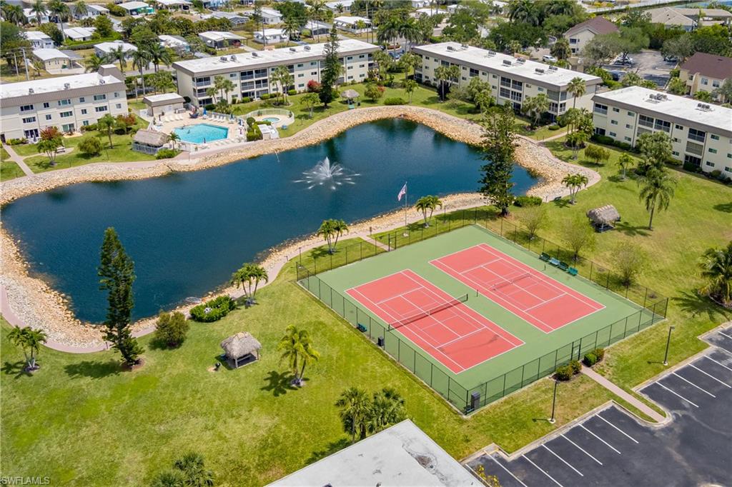 Community amenities featuring a large central pond with a fountain, two tennis courts, a swimming pool, and multiple residential buildings