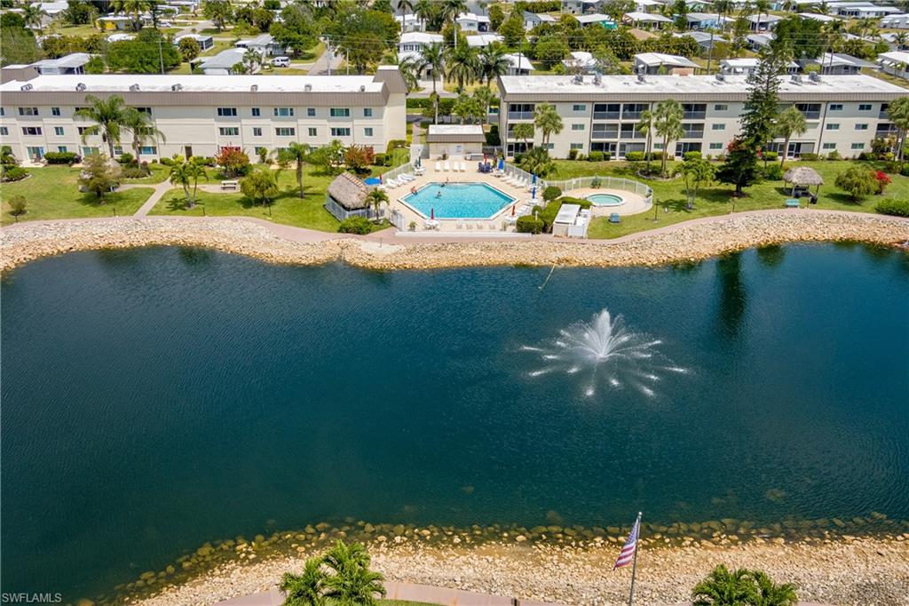 Community complex featuring two multi-story buildings, a central swimming pool with surrounding patio, and a water feature with a fountain