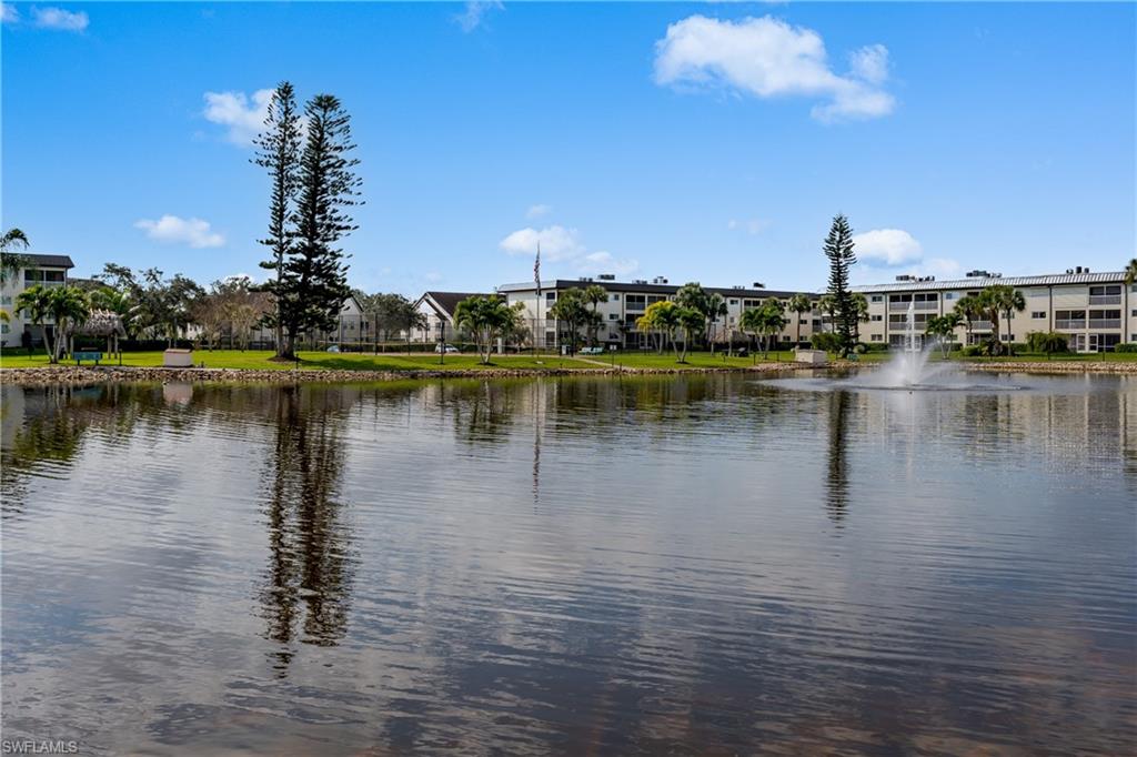 Waterfront property featuring a fountain, mature trees, and landscaping