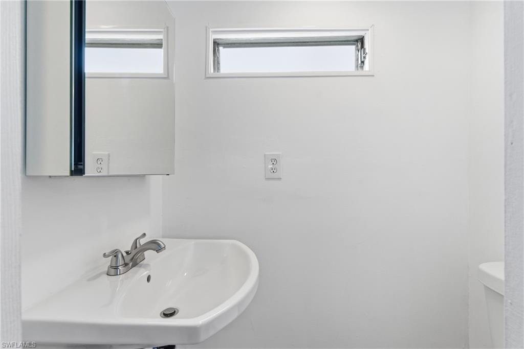 En suite half bathroom featuring a sink, toilet, and mirrored medicine cabinet