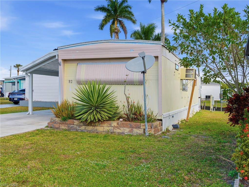 View of property exterior with a lawn, concrete driveway, and a carport