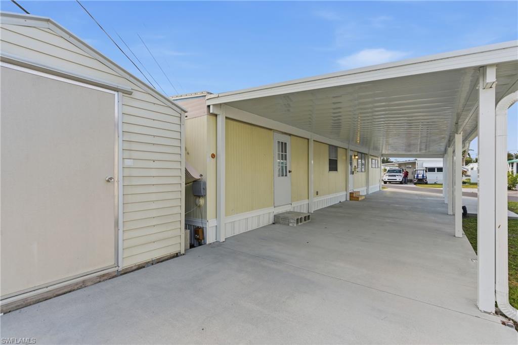 View of paved driveway featuring a carport and a shed