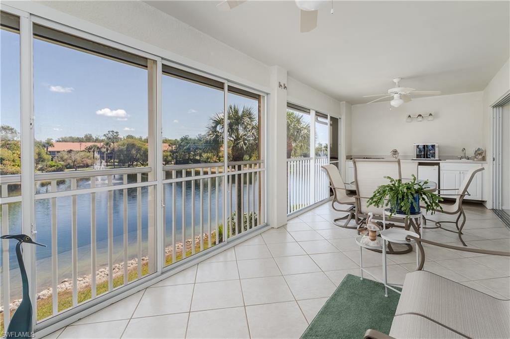Enclosed patio featuring sliding glass doors, white tile flooring, ceiling fans, and a built-in wet bar with cabinetry