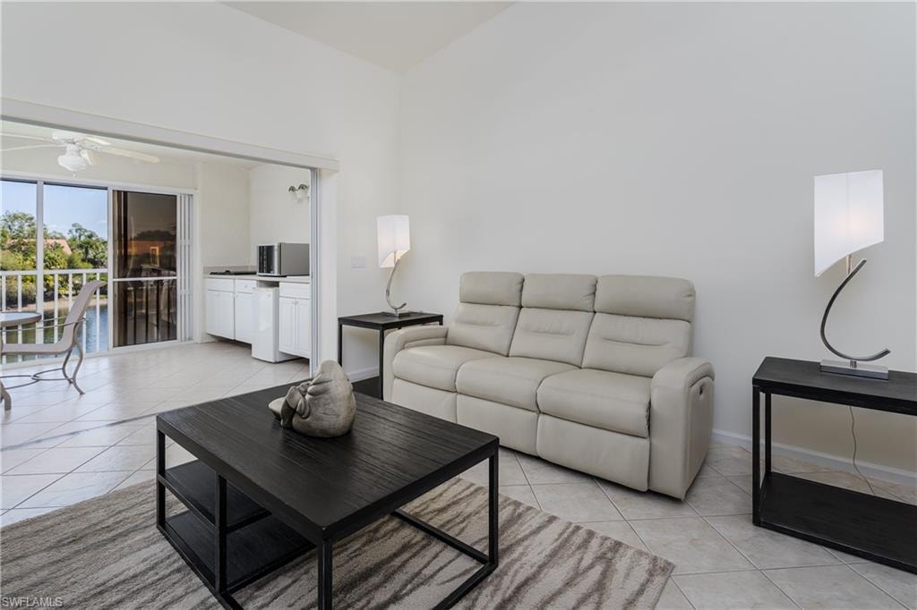 Vaulted ceiling living area featuring tile flooring, white walls, and sliding glass doors opening to a balcony