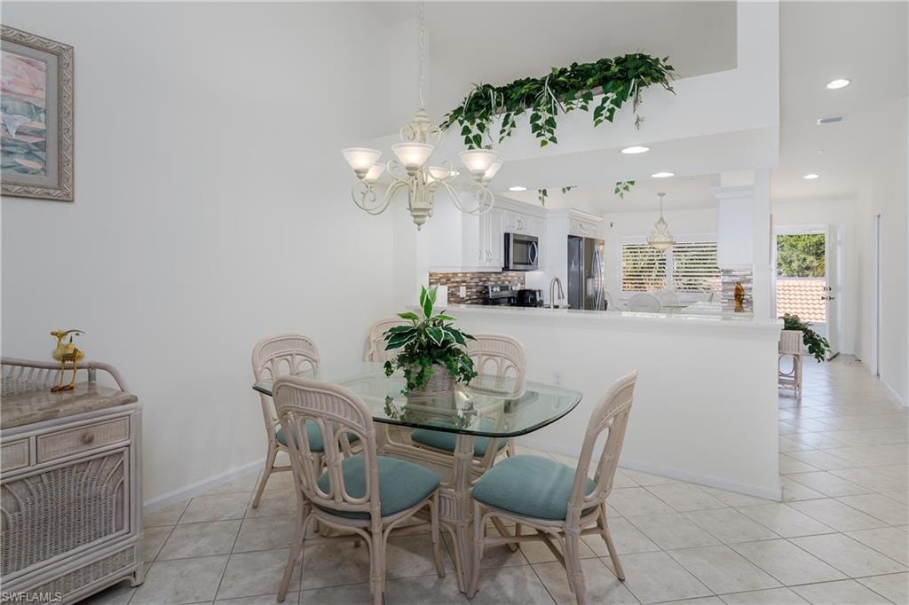 Dining area with a five-light chandelier, vaulted ceilings, and tile flooring