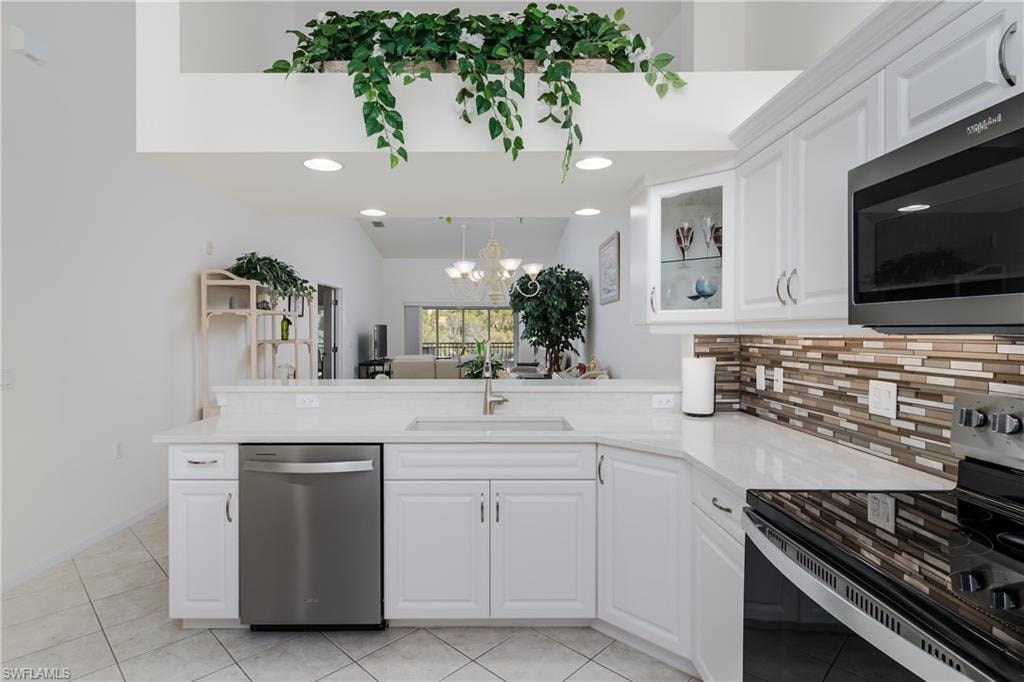 Modern kitchen featuring white cabinetry, light-toned countertops, and a mosaic tile backsplash