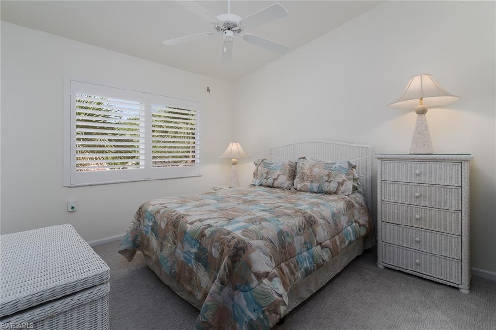 Bright interior room featuring a window with white plantation shutters, a ceiling fan, and light-colored wall-to-wall carpeting