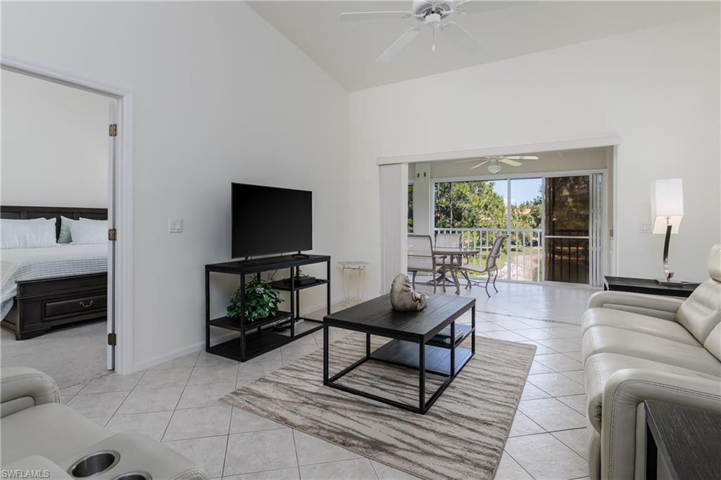 Living area featuring vaulted ceilings, tile flooring, and sliding glass doors opening to a screened balcony