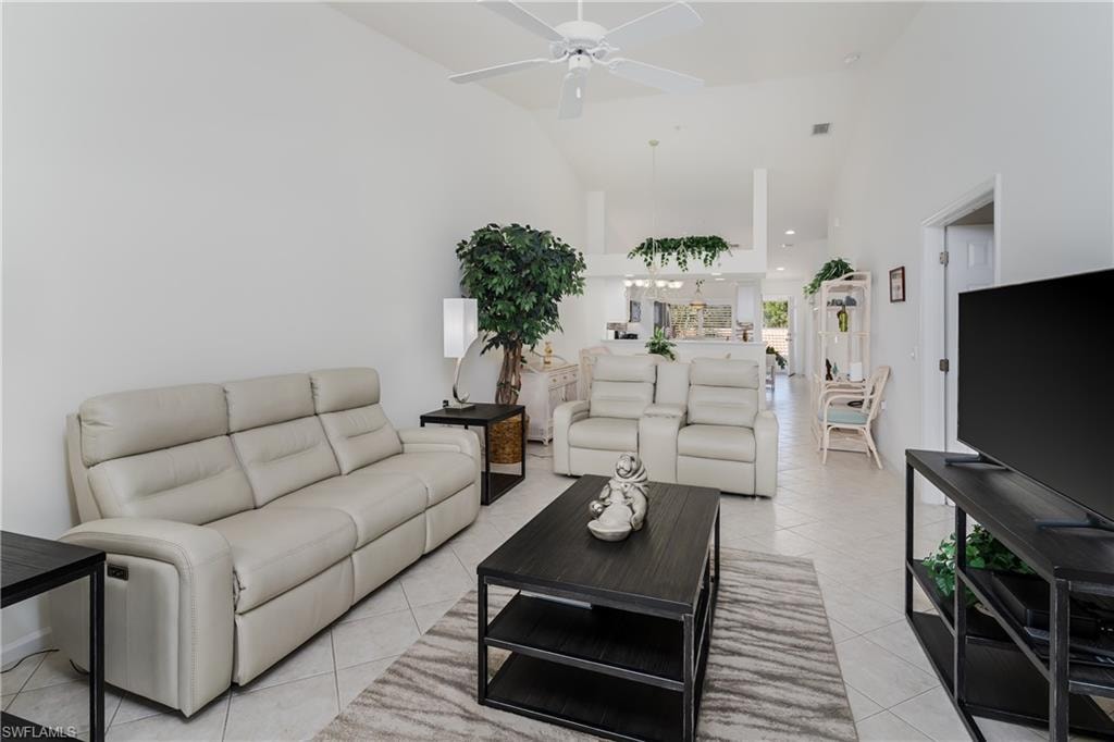 Open-concept living area featuring vaulted ceilings with a ceiling fan, light-toned tile flooring, and white wall finishes