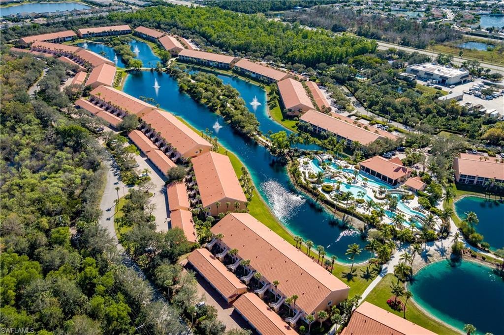 Expansive aerial perspective showcasing a resort-style property with multiple buildings, extensive water features, and lush landscaping