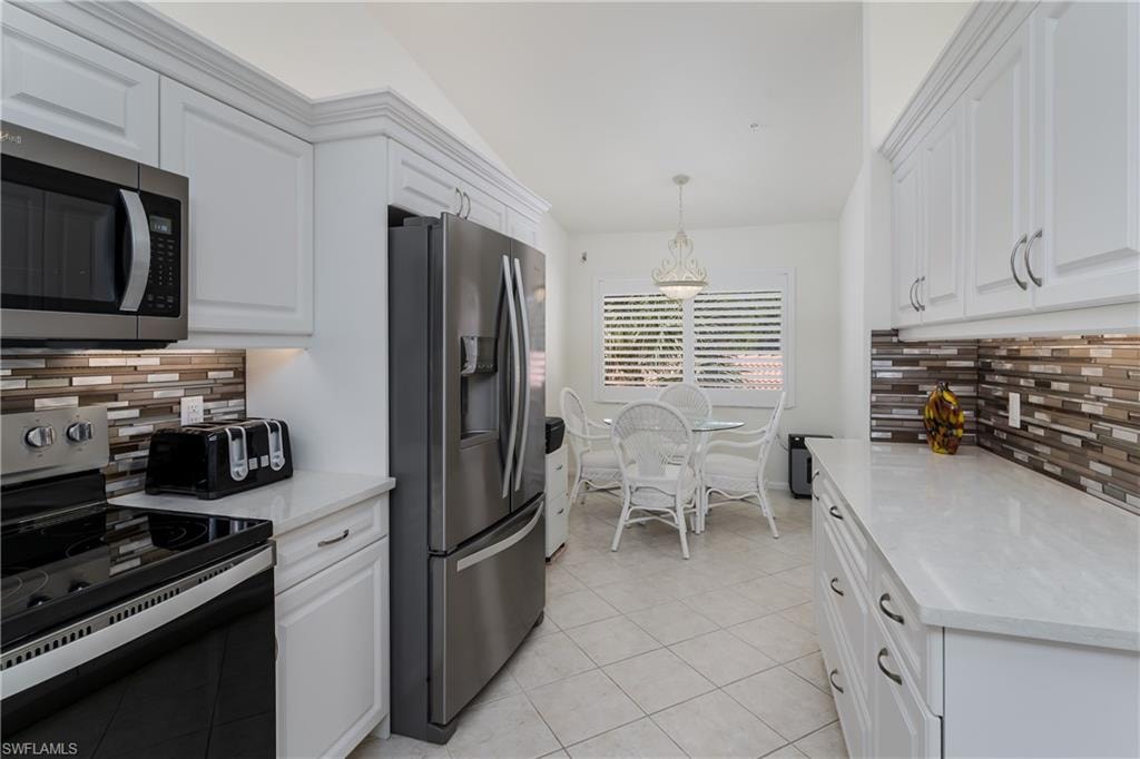 Kitchen featuring white shaker-style cabinetry, stainless steel appliances, a mosaic tile backsplash, light-toned countertops, and diagonal tile flooring