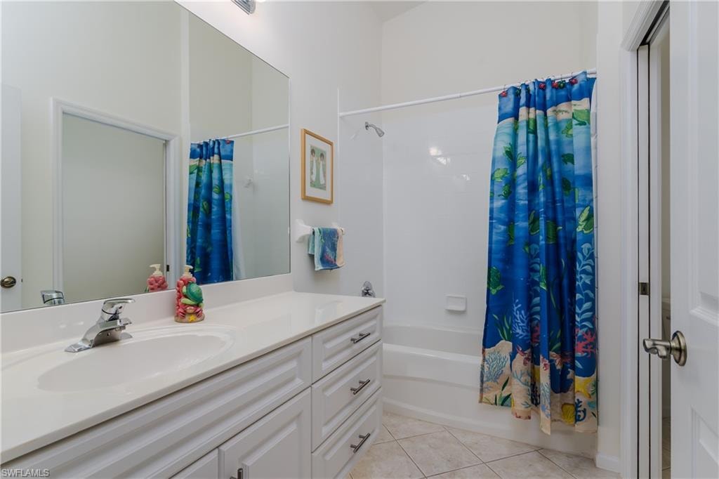 Bathroom featuring a white vanity with integrated sink, chrome faucet, white paneled cabinetry with silver hardware, large wall-mounted mirror, and a tub/shower combination