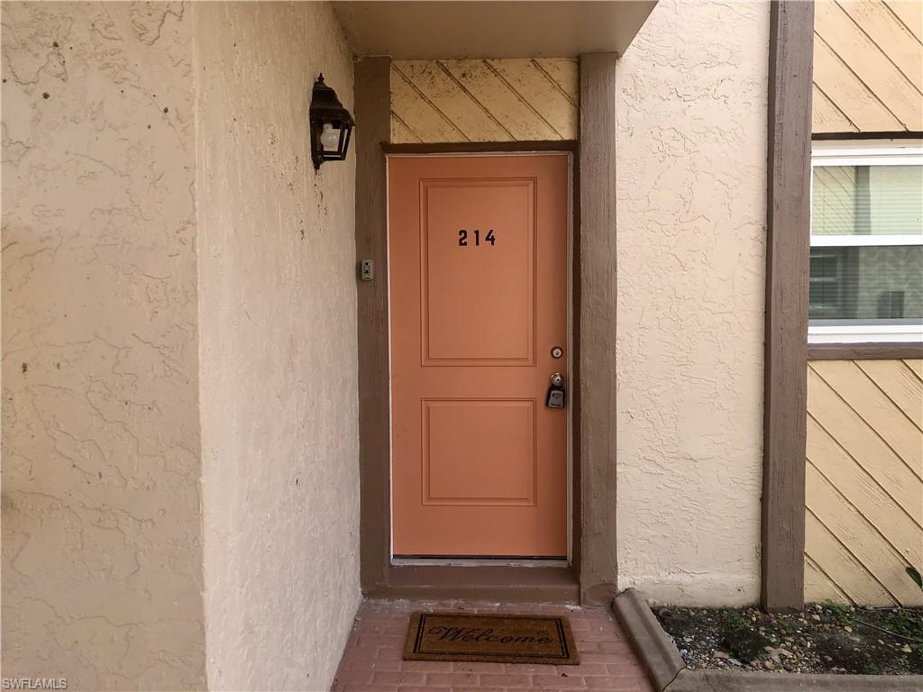 Entry door featuring a panel design, a numeric address, and a wall-mounted exterior light fixture