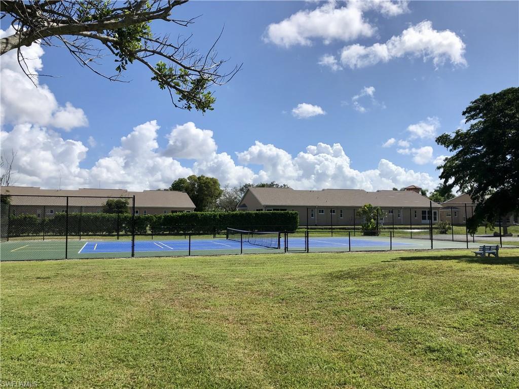Community sports courts featuring a blue and green tennis court, surrounded by fencing and manicured lawns