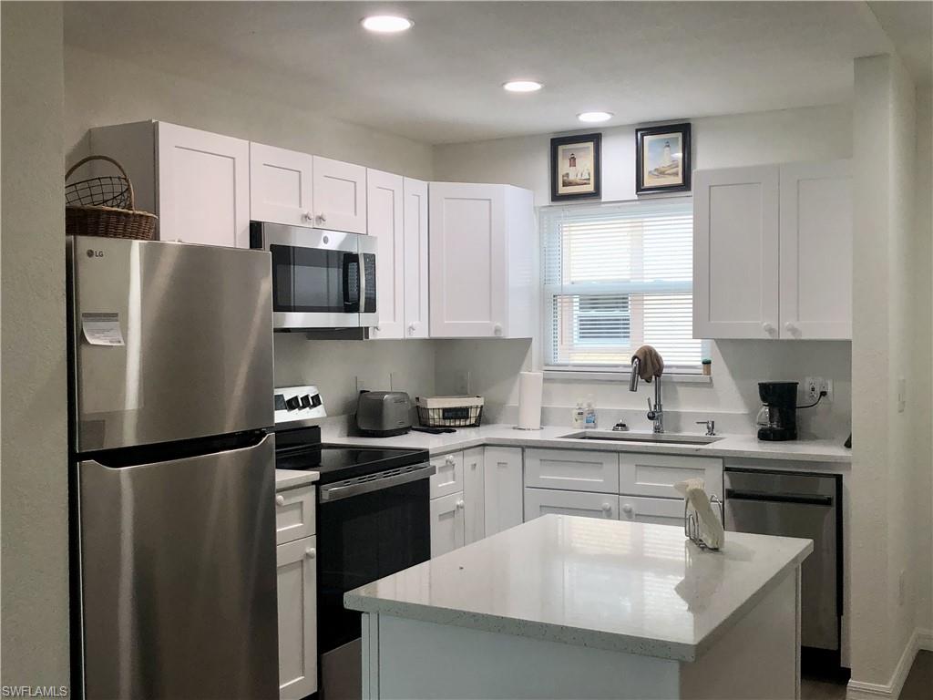 Kitchen featuring white shaker-style cabinetry, stainless steel appliances, a white quartz island, and recessed lighting