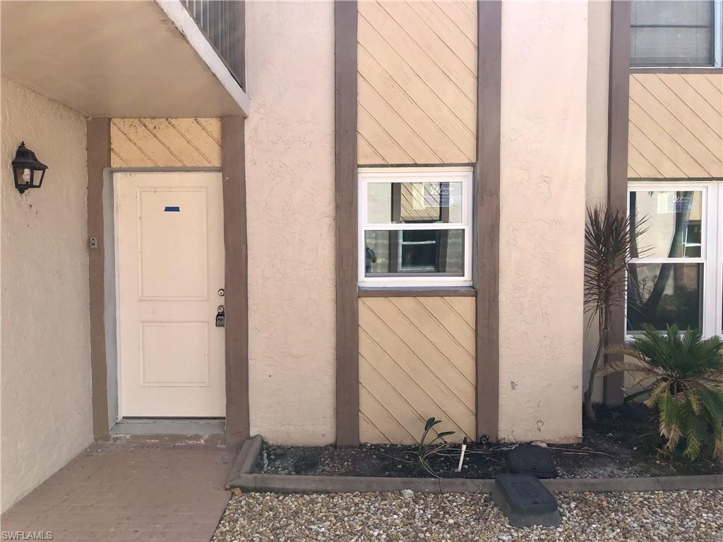 Exterior entryway featuring a paneled door, wall-mounted light fixture, and textured siding details