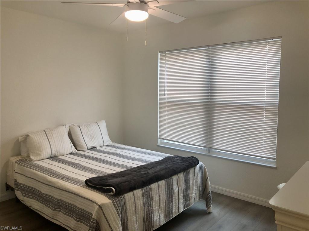 Light-filled room featuring wood-finish flooring, a window with horizontal blinds, and a ceiling fan with integrated lighting