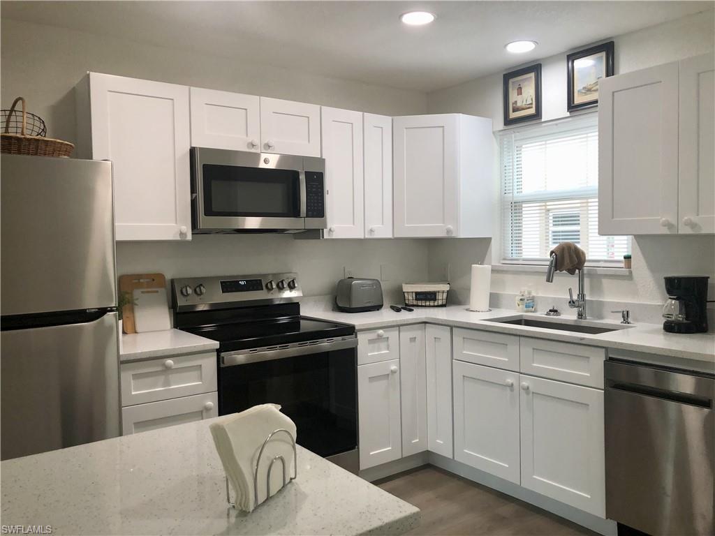 Contemporary kitchen featuring white shaker-style cabinetry, quartz countertops, and stainless steel appliances