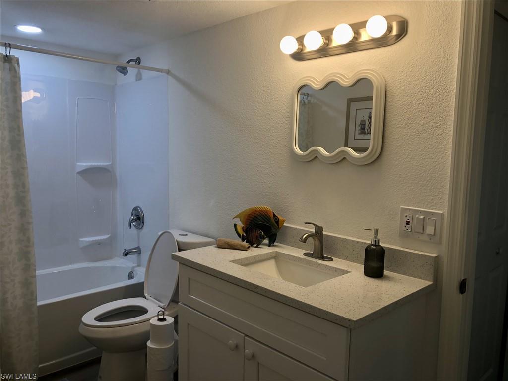 Full bathroom featuring a white vanity with a speckled countertop, undermount sink, and brushed nickel faucet