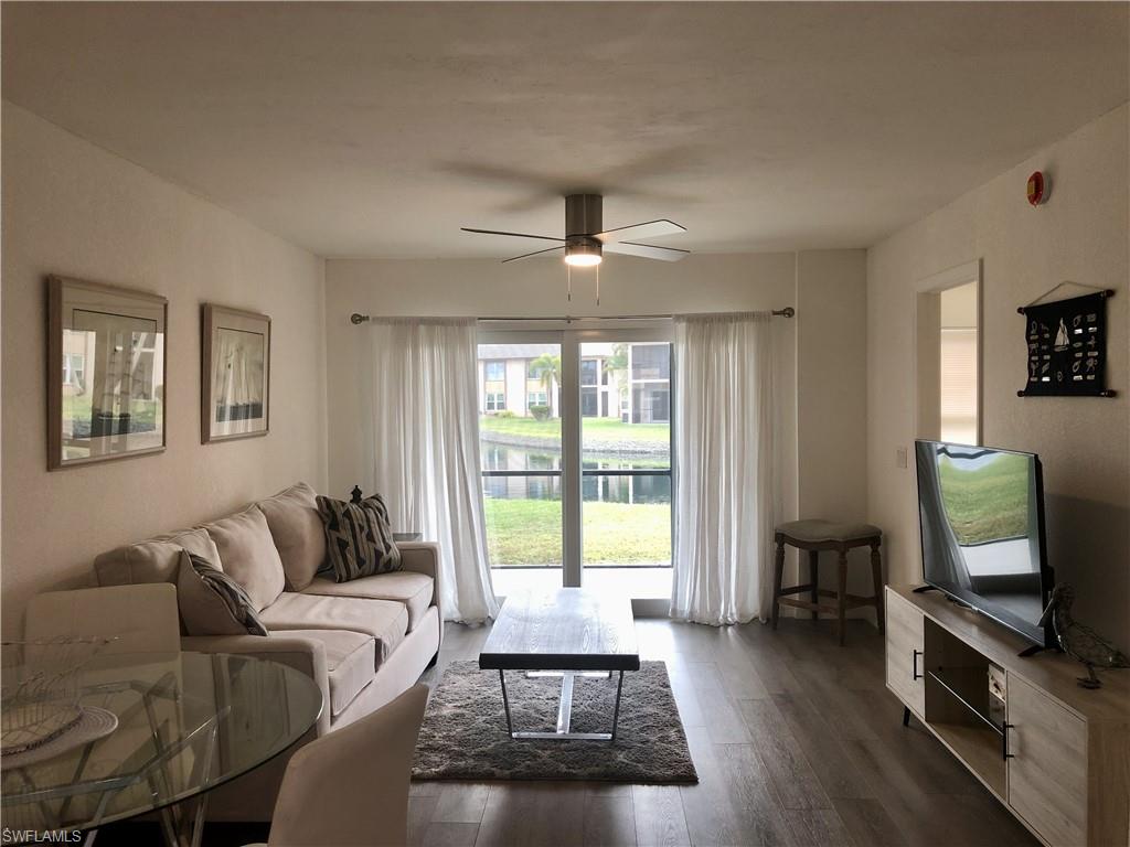 Living space featuring wood-finish flooring, a ceiling fan with integrated lighting, and a glass sliding door providing access to the exterior