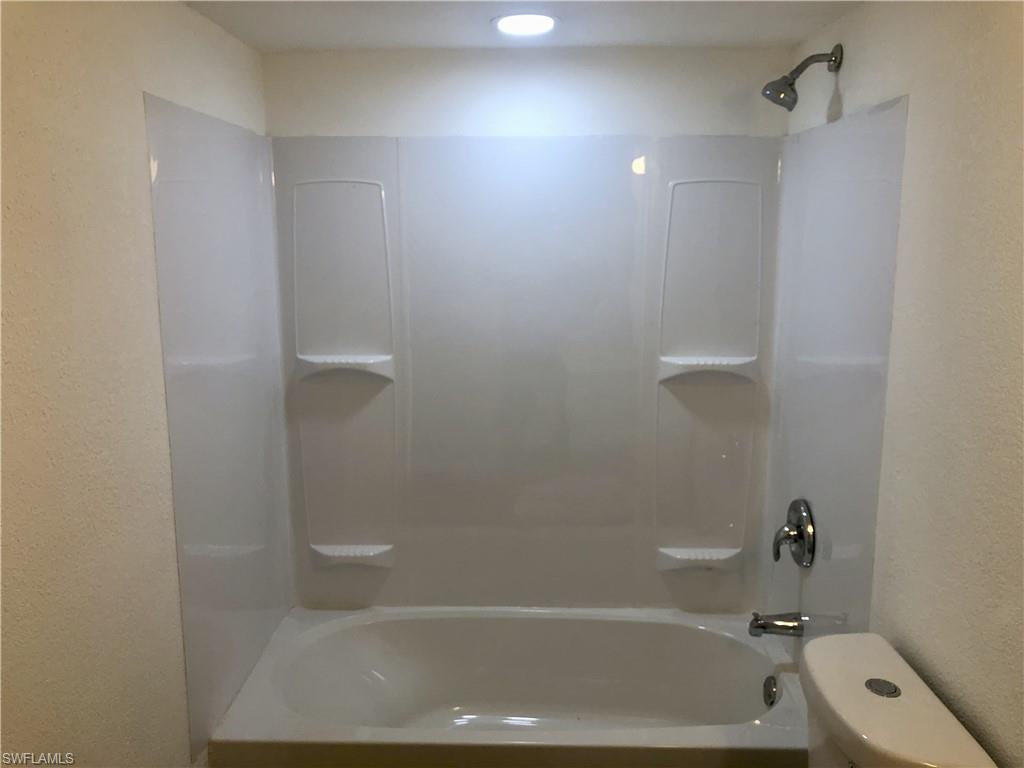 White bathtub with a coordinating shower surround featuring integrated shelving