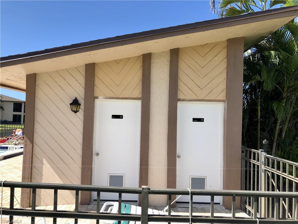 Exterior building featuring angled siding patterns, two white utility doors with metal grates, and a wall-mounted outdoor light fixture