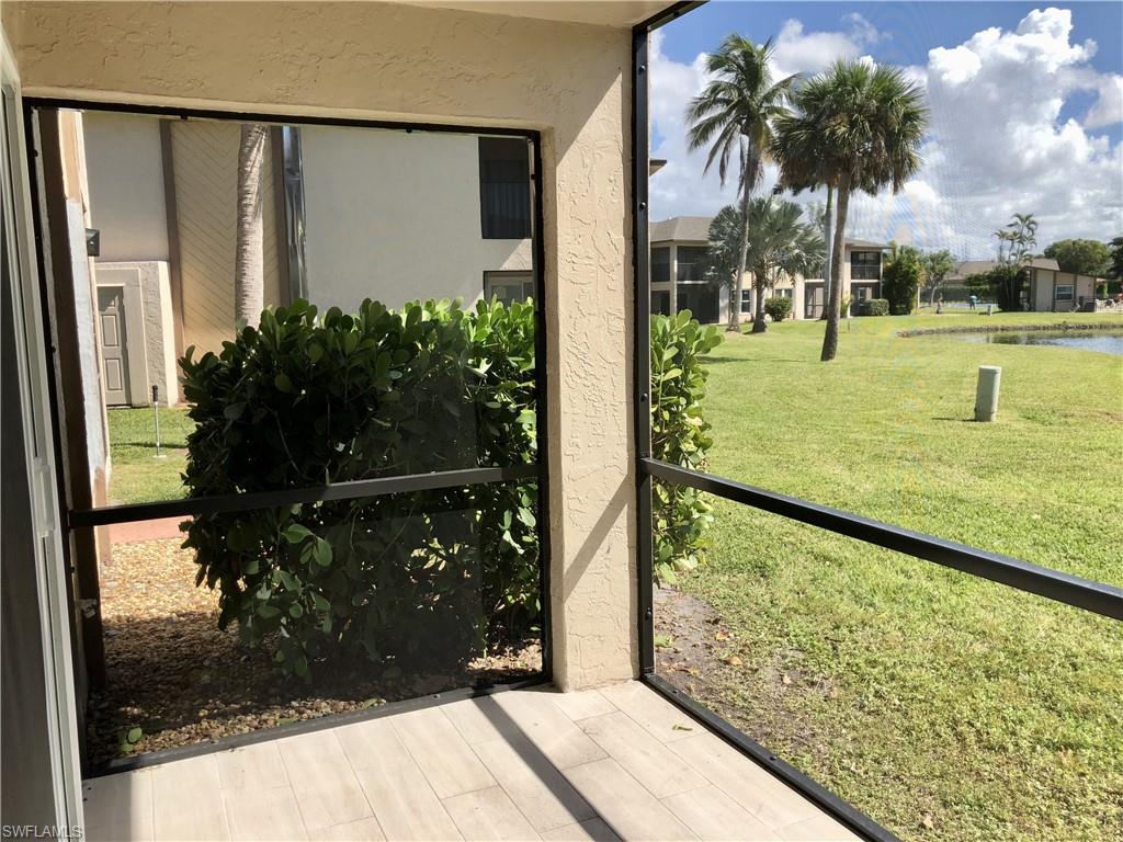 Screened outdoor space with wood-finish flooring, overlooking a green lawn and a pond