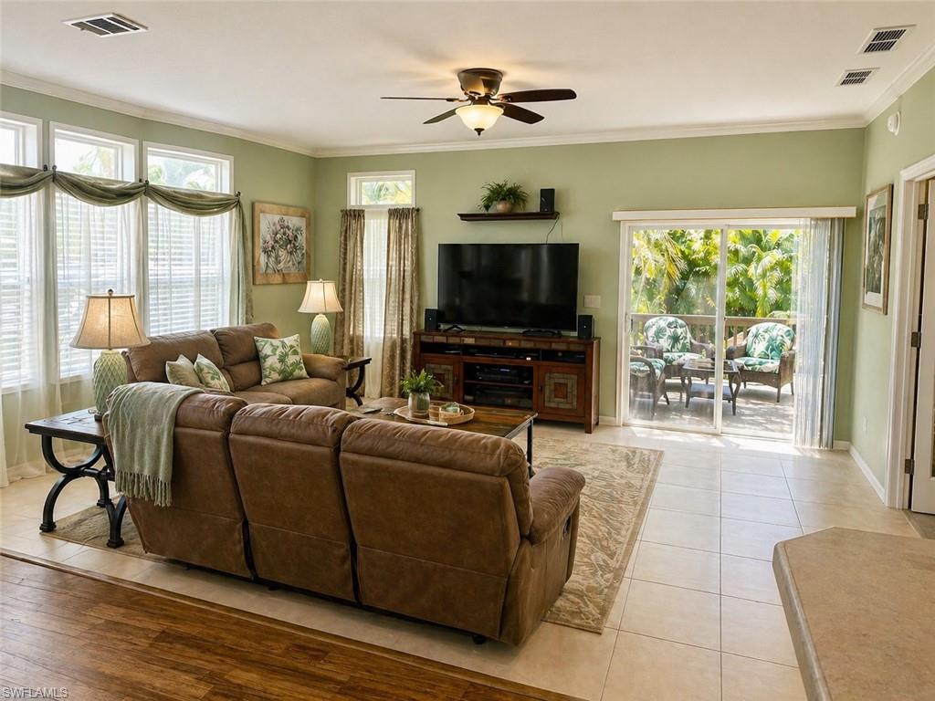 Spacious living area featuring light-toned tile flooring, an integrated ceiling fan with lighting, and multiple windows with white blinds