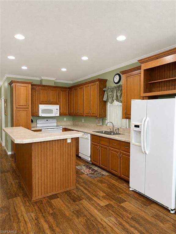 Kitchen featuring wood-finish flooring, recessed ceiling lighting, light-toned countertops, and extensive wood cabinetry with an integrated breakfast bar