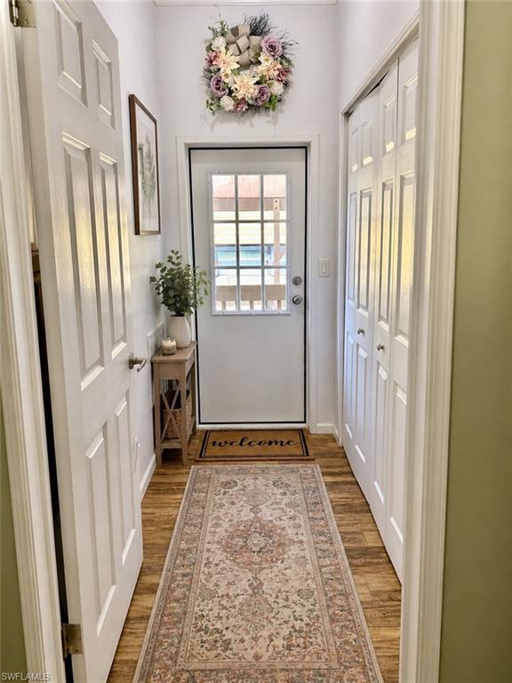 Entryway featuring wood-finish flooring, a paneled door with glass inserts, and white bi-fold closet doors