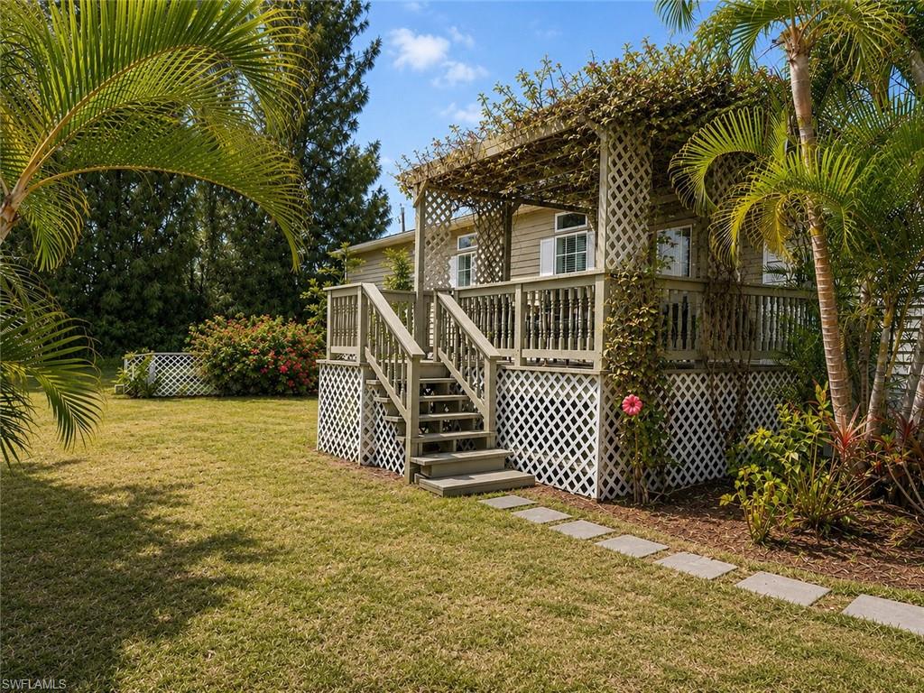 Raised deck with lattice skirting, wood pergola with climbing vines, and tropical landscaping