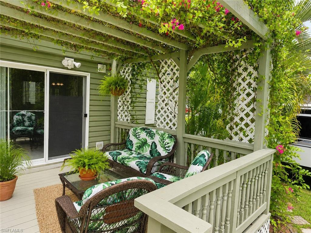 Outdoor patio featuring a pergola with mature vines and pink blossoms, wood-finish decking, and white lattice panels
