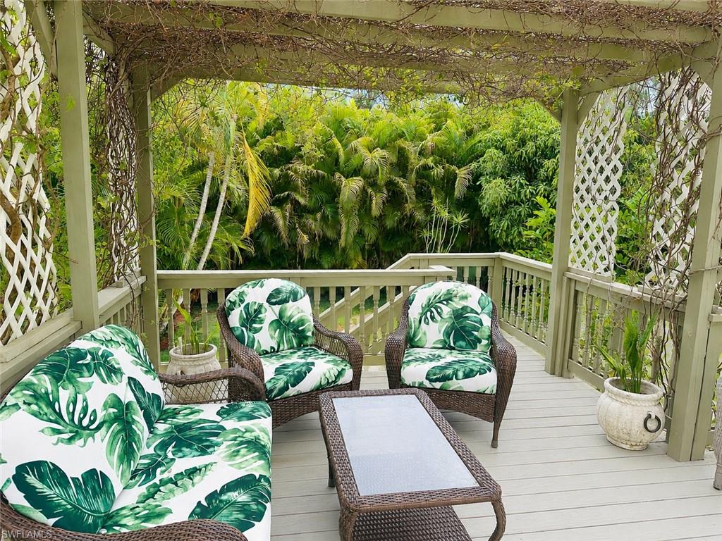 Expansive outdoor deck featuring a light-toned wood-finish surface, a substantial wooden pergola overhead, and white lattice panels